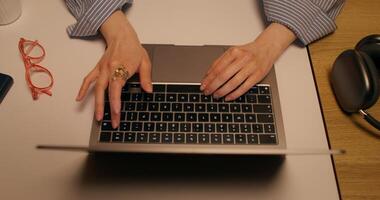 A woman typing on a laptop keyboard sitting at a table indoors, close-up of her hands, top view, unrecognizable person - keyboard photo