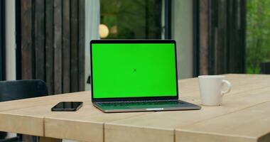 An open laptop with a green screen is on a table on the terrace of a stylish cottage. - terrace photo