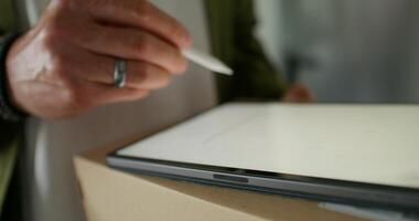 The man signs with a stylus on the tablet confirming receipt of the parcel. close-up of his hands, an unrecognizable person - person photo