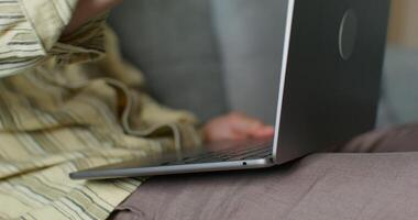 A man is typing on a laptop keyboard, holding it on his lap. Close-up of his hands, an unrecognizable person photo