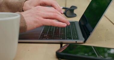 A man is typing on a laptop sitting at a table. Close-up of his hands, an unrecognizable person - unrecognizable photo