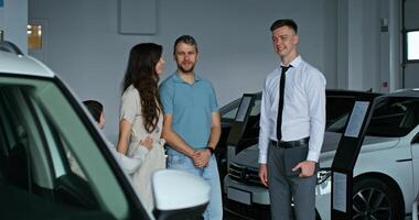 A man and woman standing next to a car in a showroom photo