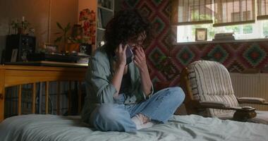 A young woman is talking on a mobile phone sitting at home with a sad look - talking photo