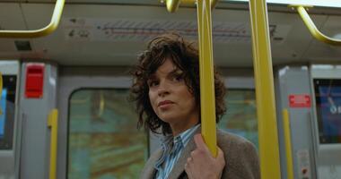 A woman rides in a train carriage in the subway, she stands and holds on to the handrail - handrail photo