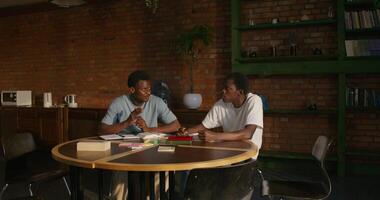 Two men are talking while studying the Bible together. They are sitting at the table indoors - sitting photo