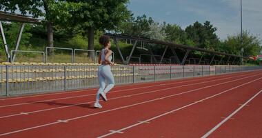 A woman in sports clothes running at the stadium on a summer day, rear view, unrecognizable person photo