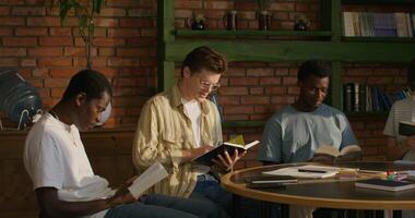 A group of young people of different nationalities join hands and begin prayer while sitting at a table indoors. Daylight - nationalities photo