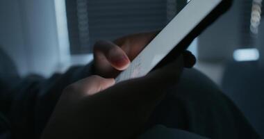 A woman uses a mobile phone while sitting in a dark room. Close-up of her hands, an unrecognizable person photo