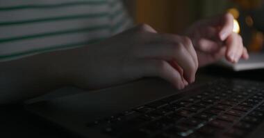 A woman typing on a laptop keyboard while sitting at a table in the dark. Close-up of her hands, an unrecognizable person. - keyboard photo