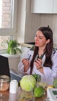 A doctor sits at a table and communicates with patients via a laptop. Holds a glucometer in his hands. Nutrition consultation for people with diabetes. Therapeutic nutrition, diet, health. video