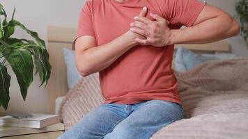 Close-up Man experiencing sharp pain in chest, holding hands on sore spot. Heart attack or infarction. Cardiovascular diseases video