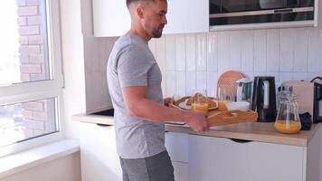 Romantic morning. Man serving breakfast with croissants and orange juice on a tray for himself and his wife. Concept. Food blogs video
