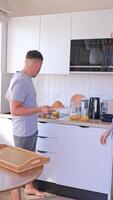 A husband and wife enjoy a cozy morning breakfast with croissants and coffee in their kitchen. They have fun chatting with each other. video