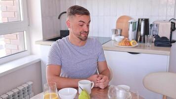 A man hasn't had enough sleep, yawns, and tries to perk up over breakfast in the kitchen at home. Lack of sleep, illness, feeling unwell, lack of energy video
