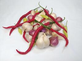 Garlic, onion, and fresh chili arranged in a white background photo