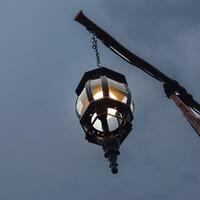 Hanging lantern glowing under evening sky with vintage metal fixture lamp photo