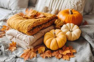 Cozy autumn still life with pumpkins and warm textiles at home photo