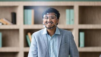 In a modern office, Indian guy smiles as facial recognition scans their face, showcasing the rise of advanced identification methods and our increasing reliance on technology. photo