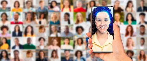 A person holds a smartphone displaying a facial recognition scan. The background features a collage of diverse faces, highlighting the impact of technology on identification processes. photo