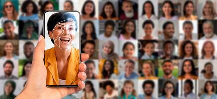 A hand holds a smartphone displaying a face recognition scan of a smiling individual. Behind are portraits of various people's faces, showcasing modern identification technology in action. photo