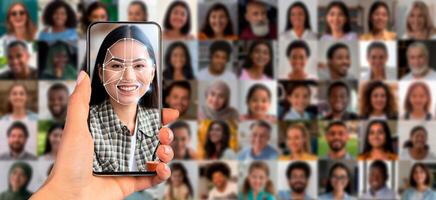 A person holds a smartphone displaying a facial recognition scan. Behind them is a collage of various faces. This highlights advancements in identification technology in a contemporary setting. photo