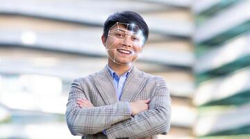Asian man stands with arms crossed, smiling confidently as facial recognition technology is applied. This modern approach is increasingly used for identification in various urban settings. photo