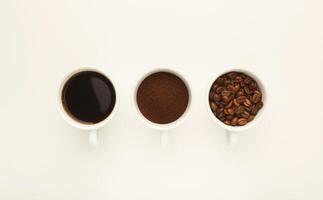 Assortment of coffee in cups. Whole beans, ground coffee and freshly brewed americano isolated on white background, top view, copy space photo