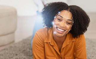 African American woman with curly hair smiles while facial recognition technology processes her features. This scene captures the integration of modern identification methods in a casual setting. photo