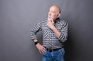 Pensive mature man looking away, copy space. Senior male dreaming about something, lost in thoughts, gray studio background photo