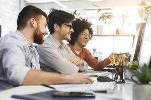 Great job. Three men enjoying good coding job on computer at modern office, empty space photo