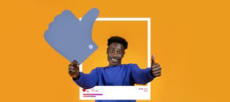 A person is enthusiastically giving a thumbs up while posing with a large like icon. The bright orange background highlights the energy of social media influence, perfect for content creation. photo