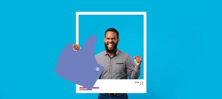 A man joyfully poses with a thumbs up gesture against a bright blue backdrop. He exudes enthusiasm, embodying the spirit of an online influencer sharing content with followers. photo