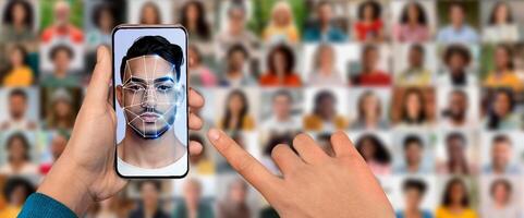 A hand holds a smartphone that scans a face for identification, demonstrating advanced facial recognition technology. Multiple portraits of people in the background enhance the modern feel. photo