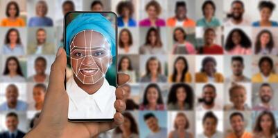 A hand holds a smartphone displaying a face scanning interface, illustrating the advanced technology of identification. In the background, a diverse collage of faces highlights various individuals. photo