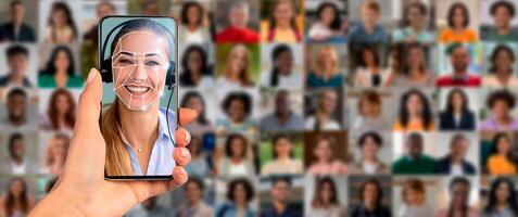 A woman scans her face using a smartphone, showcasing advanced facial recognition technology. Multiple faces are visible in the background, highlighting modern identification methods. photo