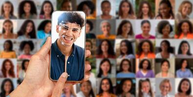 A person holds a smartphone displaying a facial recognition scan of their face, surrounded by multiple portraits of different individuals, illustrating advanced identification technology in use. photo