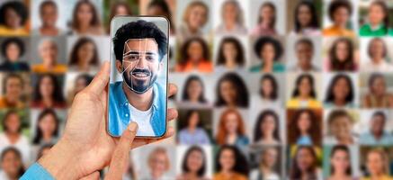 A person holds a smartphone displaying a facial recognition scan of themselves. Behind them is a collage of several blurred portraits, showcasing modern technology and identification processes. photo