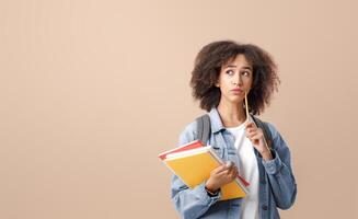 Serious question and making decision studying after quarantine. Pensive african american lady with smart watch holds notepads and press pencil to cheek and looks at free space, on light background photo