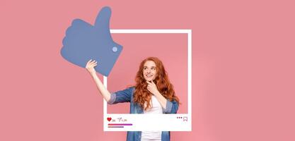 A social media influencer showcases a thumbs up gesture as she interacts with a large mock-up frame. The background features a bright pink color, creating a lively atmosphere for online content. photo