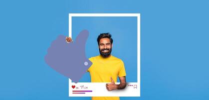 A smiling man in a yellow shirt stands against a blue background, showcasing positivity with a thumbs up gesture. He embodies the spirit of social media engagement and content creation. photo