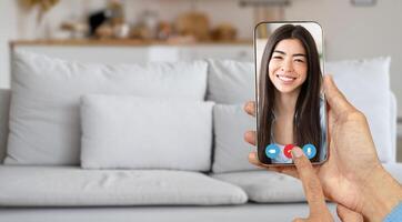 A person engages in a friendly call using a smartphone while sitting at home. The setting is casual, with a comfortable sofa in the background, illustrating modern telecommunication. photo