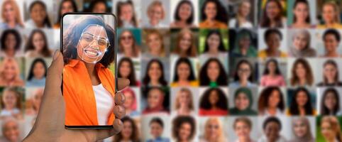 A hand holds a smartphone displaying a smiling face as it scans for identification. In the background, a collage of diverse individuals highlights the advancements in recognition technology. photo
