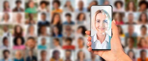 A smartphone is held in a hand, displaying a face for identification against a backdrop of various portraits. This showcases modern technology used for facial recognition. photo