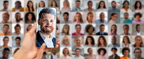 A hand displays a smartphone showing a face scan. In the background, a collage of diverse faces highlights the advancements in identification and modern technology. photo