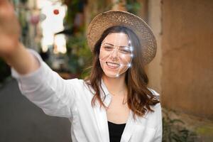 A young woman uses facial recognition technology while taking a selfie in a vibrant urban alley. The modern tech highlights her face with a grid overlay, symbolizing identification advancements. photo