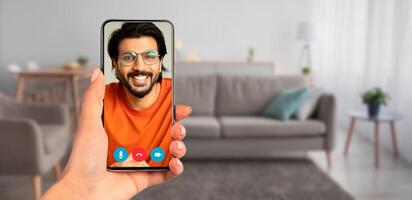 A person using a smartphone for a call in a cozy living room. The comfortable furniture and warm lighting create a welcoming atmosphere for communication. photo