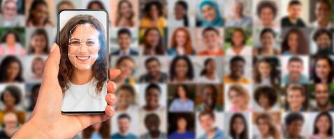 A person holds a smartphone displaying a facial recognition scan in a busy environment. Behind, a collage of diverse faces illustrates modern identification technology's extensive application. photo