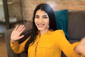 A woman smiles and waves while using facial recognition technology for identification. This scene captures the integration of advanced tech in everyday activities, reflecting the new normal. photo