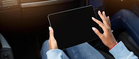 Work in road, app and modern digital map to find highway or address. Young hands of african american female work on tablet with blank screen, in passenger seat in car, cropped, pov, copy space photo