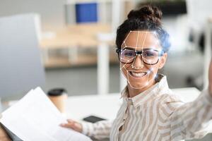 A person is using facial recognition technology while sitting at a desk in a contemporary office. They appear engaged and friendly, showcasing the ease of identification in today's work environment. photo